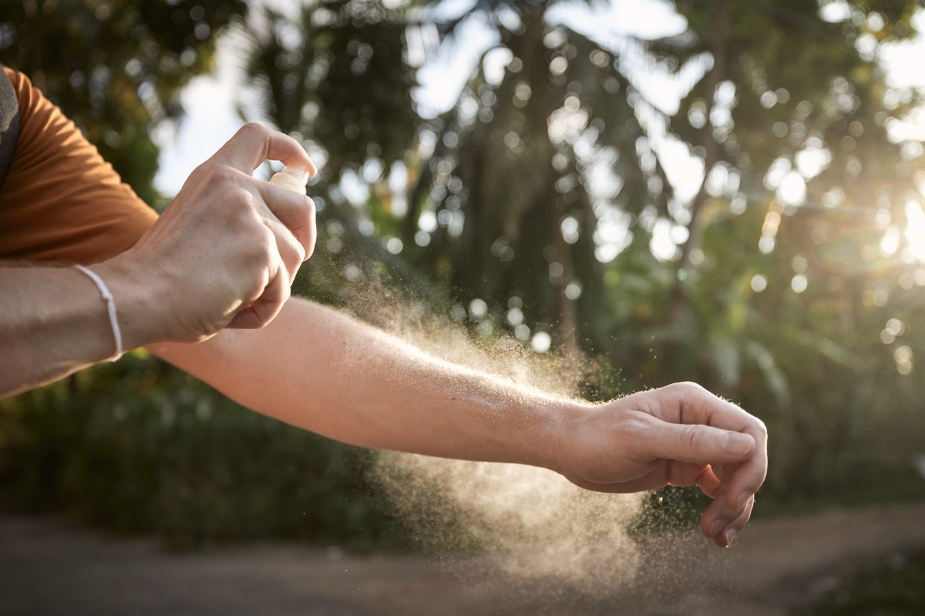 man spraying arm with bug repellent in nature